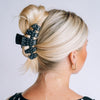 TELETIES large black claw clip with white polka dots holding thick  blonde hair in a bun updo
