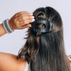 TELETIES medium flat round hair clip in black with white polka dots worn in long dark hair
