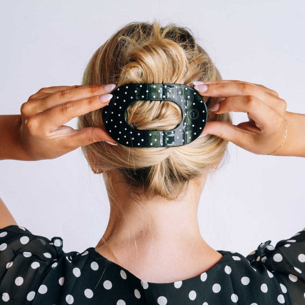 TELETIES large flat round hair clip in black with white polka dots worn in a blonde woman's hair
