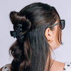 TELETIES medium black hair claw clip with white polka dots holding a half-up hairstyle on a woman
