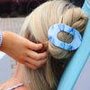 TELETIES blue marbled medium flat oval hair clip holding blonde hair in a bun.

