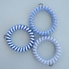 TELETIES blue spiral hair ties, sold in packs of three. One tie has blue and white stripes, the other two are solid blue with a textured pattern.
