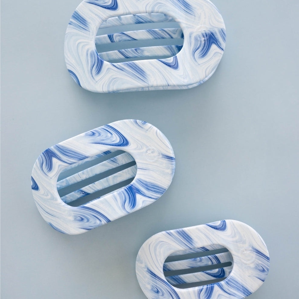 TELETIES blue and white marbled large flat round hair clip with bendable teeth for a secure hold.
