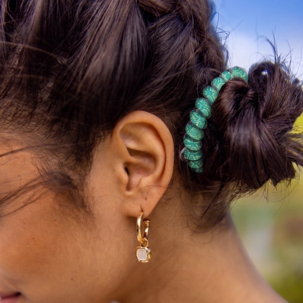 TELETIES By the Sea Shore large green hair ties with a seashell pattern, worn in a bun.
