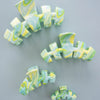 TELETIES By the Sea Shore Medium Claw Clip in green with a marbled swirl pattern of yellow and blue.

