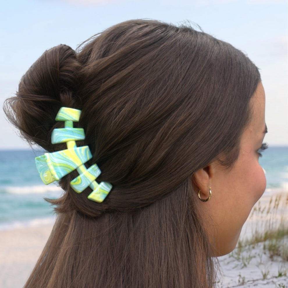 TELETIES By the Sea Shore Medium Claw Clip in green and yellow marbled acetate, holding back dark brown hair.
