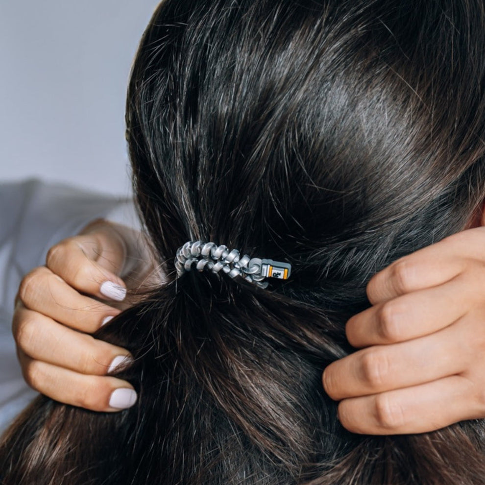TELETIES Good Hair Rx small silver spiral hair tie securing dark hair in a ponytail
