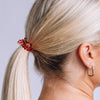TELETIES Heart and Hustle small red hair tie worn in a blonde ponytail, featuring a heart charm and spiral design.

