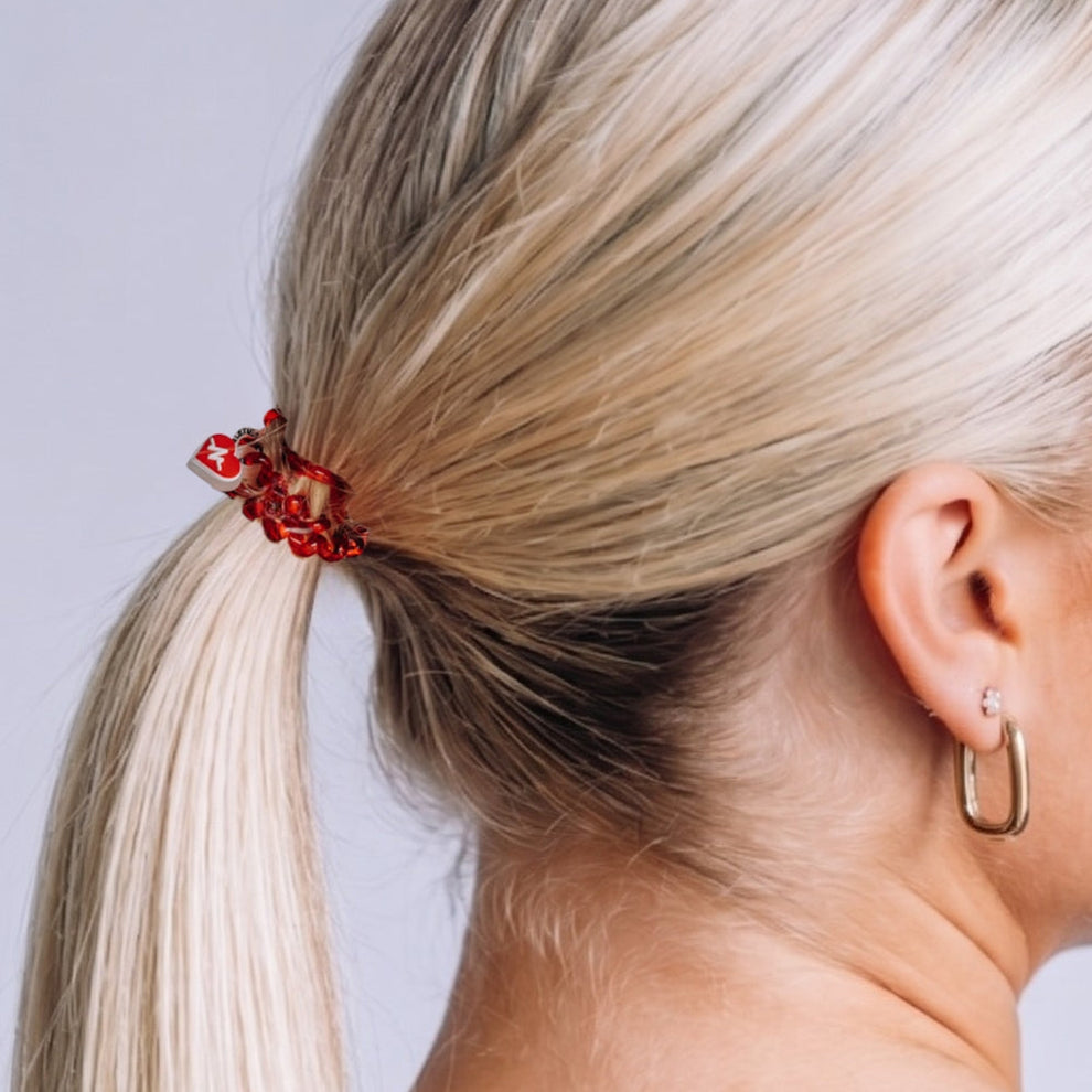 TELETIES Heart and Hustle small red hair tie worn in a blonde ponytail, featuring a heart charm and spiral design.
