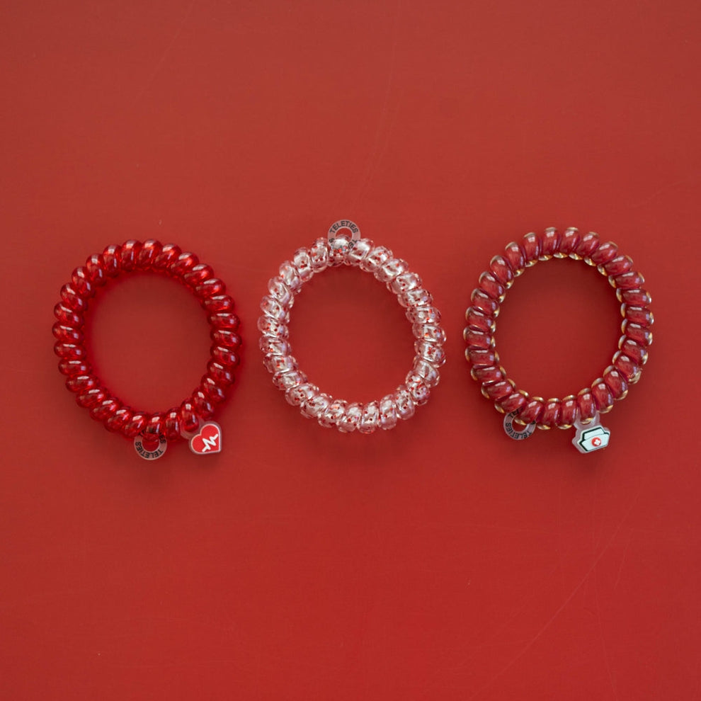 TELETIES Heart and Hustle large spiral hair ties in red and clear with medical-themed charms on a red background
