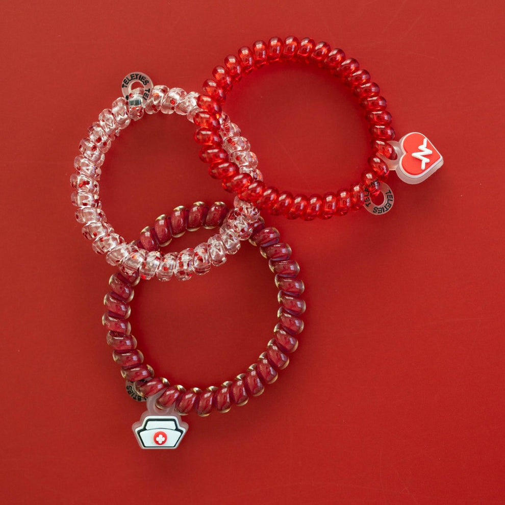 TELETIES Heart and Hustle small hair ties in red and clear spiral designs with medical-themed charms on red background
