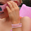 TELETIES pink and white Just Keep Swimming small hair ties worn as bracelets on a woman's wrist.
