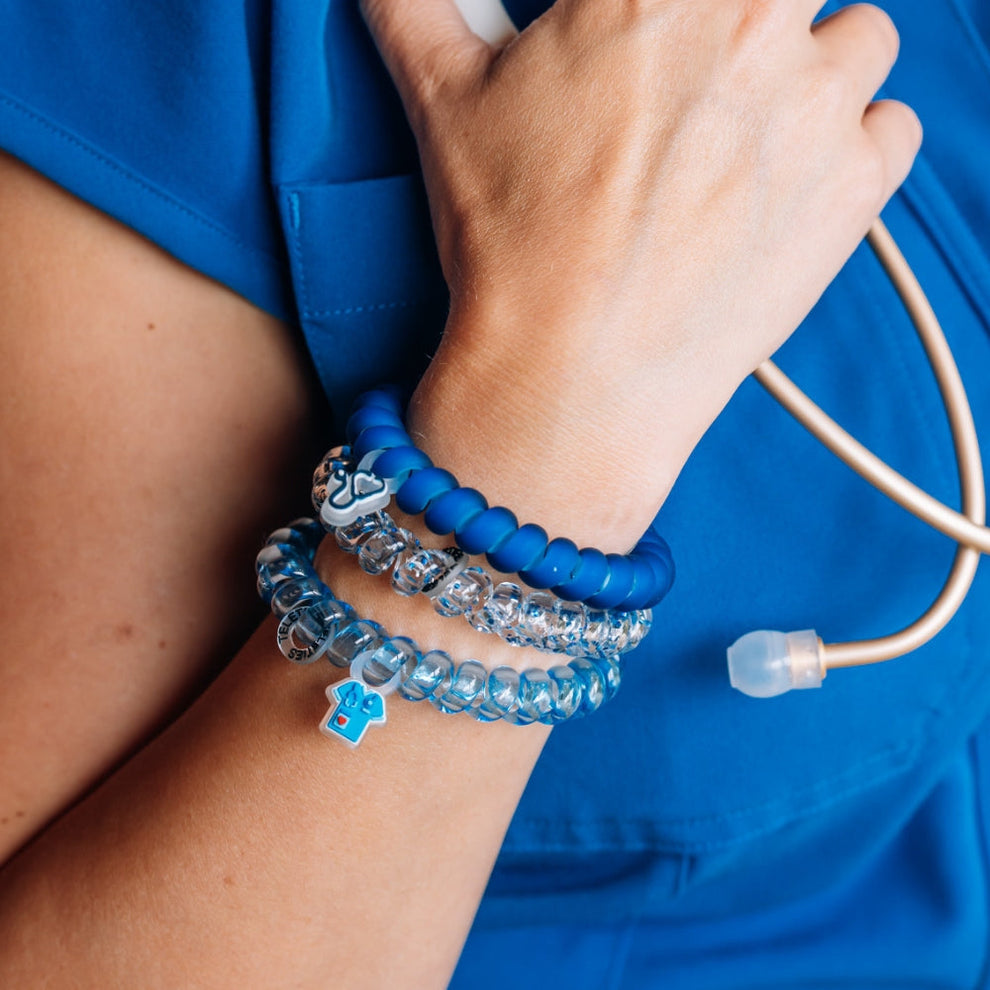 TELETIES On Call large hair ties in blue and clear worn as bracelets on a healthcare worker in blue scrubs
