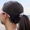TELETIES Pinch Me! Bundle hair ties in white with pink and grey pattern, holding a ponytail on a woman at the beach.
