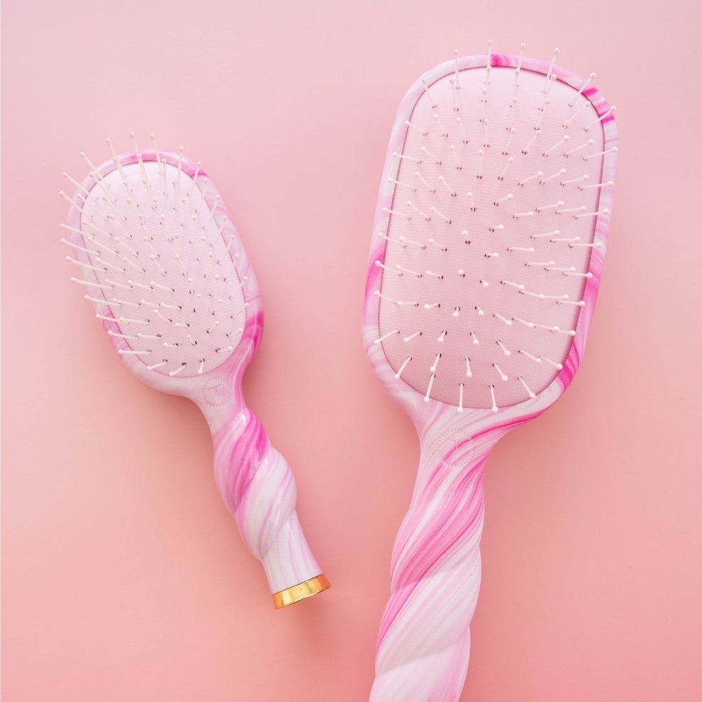 TELETIES pink and white tie-dye detangler hair brushes, one large and one small, with unique swirl patterns.
