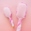 TELETIES pink and white tie-dye detangler hair brush with white bristles and a gold accent on the handle.
