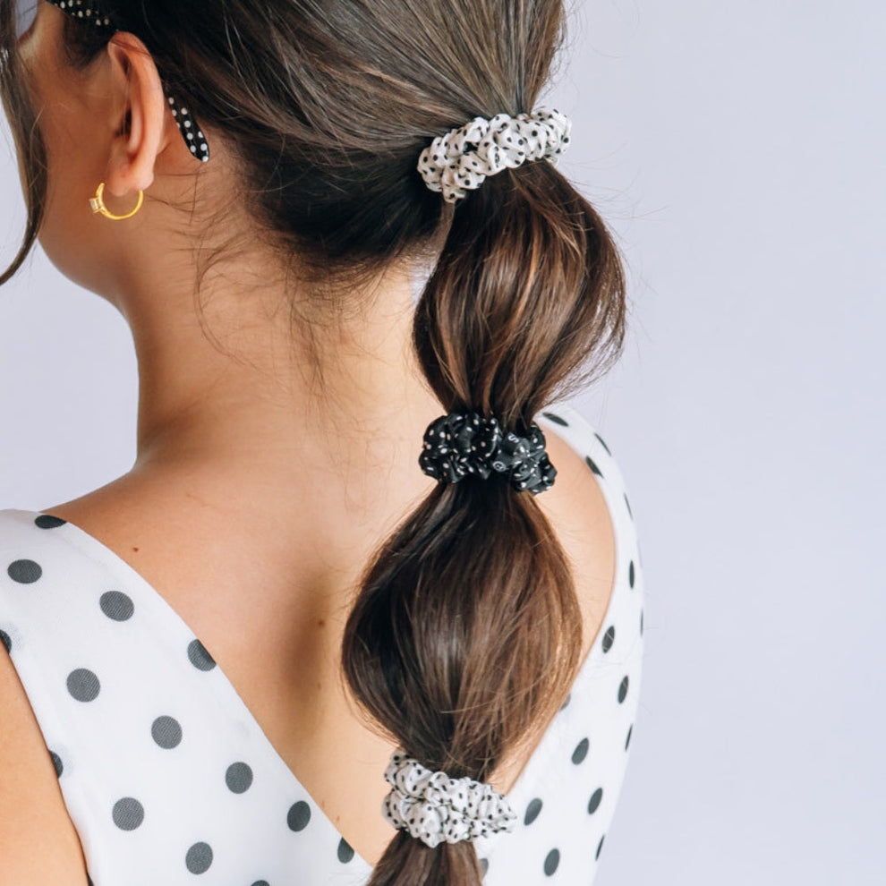 TELETIES small silk scrunchies in black and white polka dot print worn in a segmented ponytail on a woman
