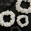 TELETIES small silk scrunchies in black and white polka dot print with inner coil grip on a matching patterned background
