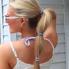 TELETIES small blue and white striped spiral hair ties worn in a blonde woman's ponytail and as a bracelet.
