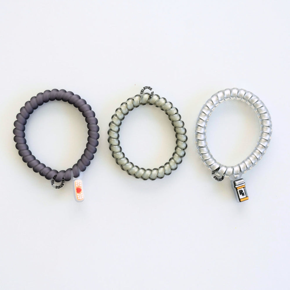 TELETIES Good Hair Rx small spiral hair ties in grey, clear, and silver with medical-themed charms on a white background
