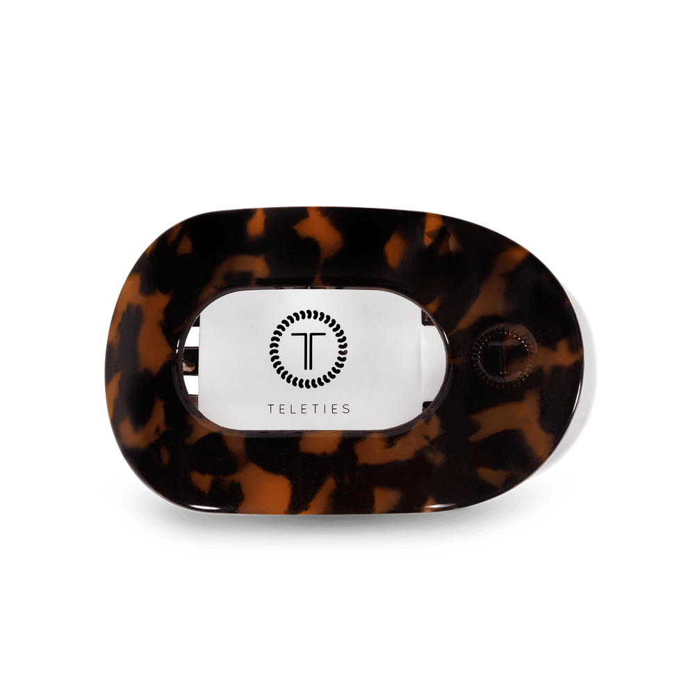 TELETIES Tortoise small Flat Round Hair Clip with a brown tortoiseshell pattern. Its flexible teeth provide a secure hold, making it nearly unbreakable. The clip is neutral in color, lightweight, and its flat design enhances comfort when laying flat, workouts, and driving.
