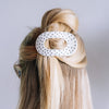 TELETIES medium flat round hair clip in white with black polka dots worn in blonde hair for a comfortable secure hold
